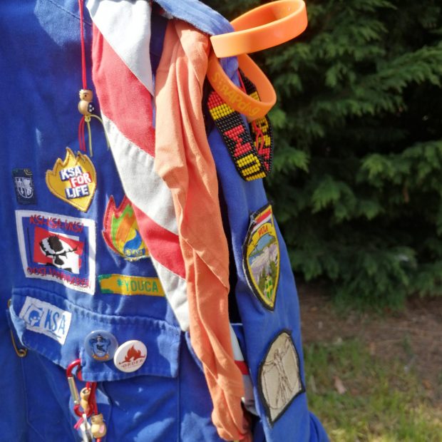 sjaaltje Het oranje sjaaltje komt opgerold om de linkermouw.